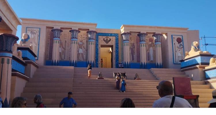 Replica ancient Egyptian temple facade with colorful columns and sphinx statues as visitors ascend wide steps.