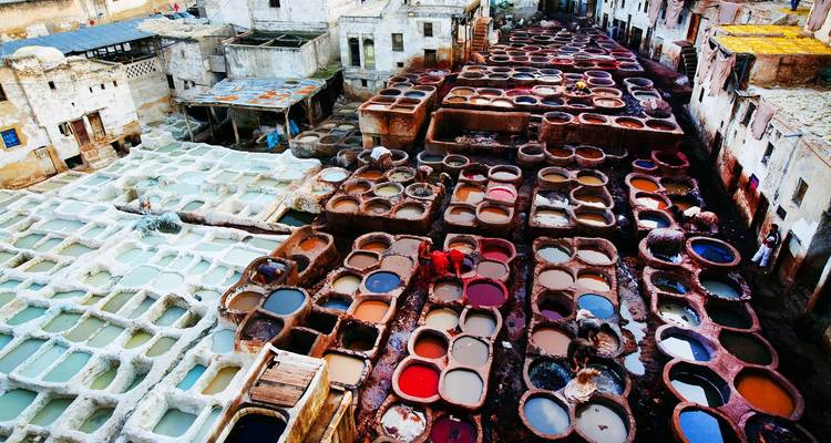 Colorful vats of dyes fill a traditional leather tannery complex viewed from above.