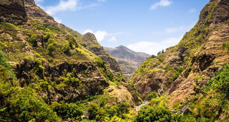 Paysage de canyon en terrasses verdoyant sur Santo Antão avec de hautes crêtes et un ciel bleu.