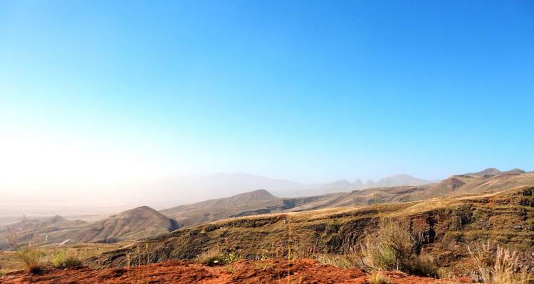 Large plateau désertique et brumeux avec des collines ondulantes sous un ciel bleu clair sur Santo Antão.