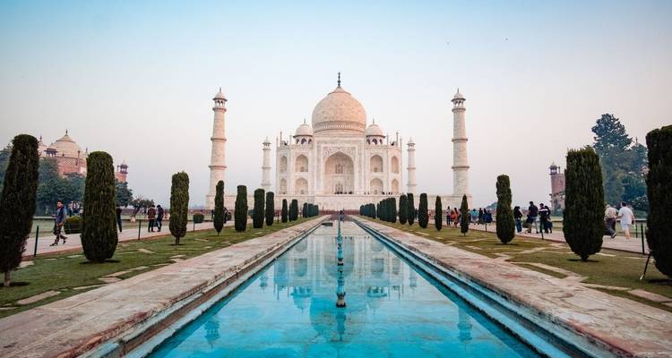 Ikonisches weißes Marmor Taj Mahal spiegelt sich in langem Reflexionsbecken bei Sonnenaufgangsfarben.