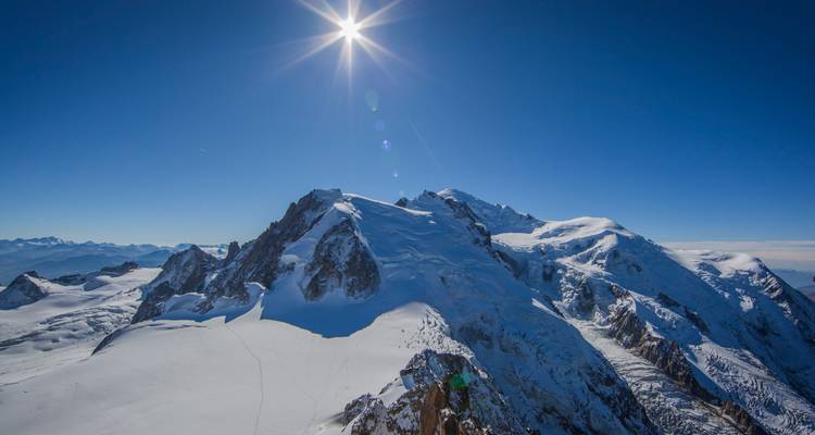 Un soleil éclatant flamboie au-dessus du sommet enneigé du mont Blanc, illuminant d'infinis glaciers alpins.