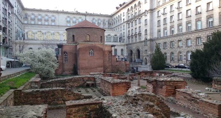 La rotonde Saint-Georges en briques rouges antiques entourée de ruines romaines and bâtiments modernes de Sofia.