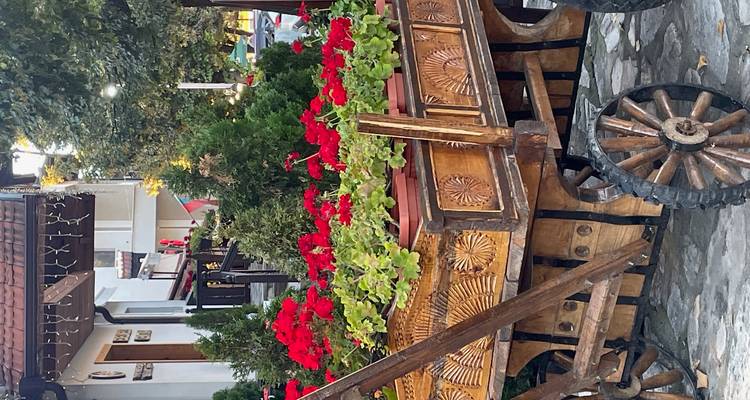 Chariot en bois artisanal rempli de fleurs rouge vif sur une rue pavée.