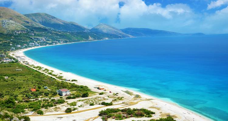 Vue panoramique saisissante d'une baie albanaise turquoise avec une longue plage de sable blanc.