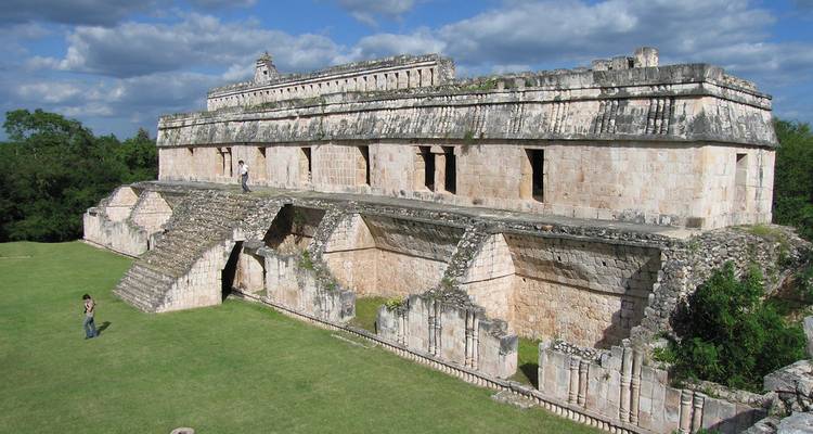 Ruines de l'ancien palais maya d'Uxmal avec un couple explorant la terrasse supérieure.