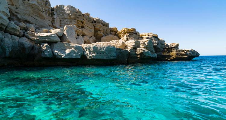 Les eaux turquoise claires des Caraïbes viennent lécher les falaises calcaires escarpées sous un ciel lumineux.
