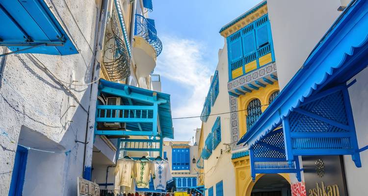 Rue étroite colorée avec des balcons à treillis bleus et des accents jaunes typiques de Sidi Bou Saïd.