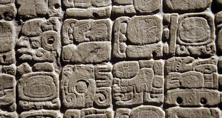 Mur de pierre détaillé sculpté avec des rangées de glyphes et symboles mayas