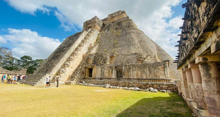 Vue latérale en angle de la pyramide d'Uxmal avec des visiteurs se promenant autour de sa base par une journée ensoleillée