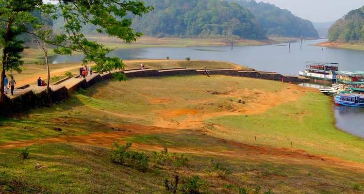 An inland lake bordered by forested hills with tour boats moored along the shore.