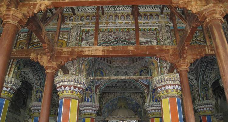 Arches complexes et plafonds peints à l'intérieur d'une salle de palais historique soutenue par des colonnes.