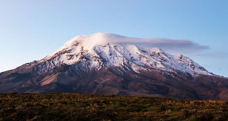 Sneeuwbedekte top van de Chimborazo-vulkaan bedekt door lenticulaire wolk bij zonsopgang boven hoogvlaktes.