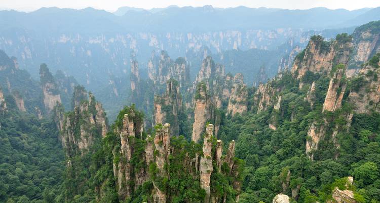 Lush green sandstone pinnacles rise from dense forest in the misty expanse of Zhangjiajie National Forest Park.