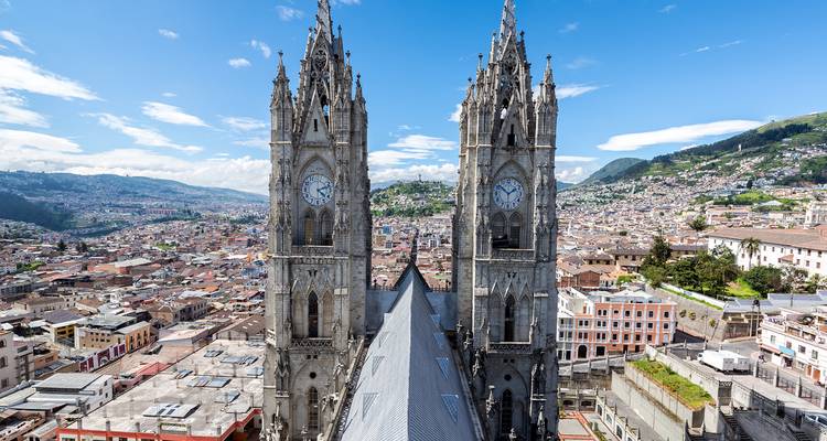 Las torres gemelas de reloj de la Basílica del Voto Nacional se elevan sobre el centro histórico de Quito y las montañas circundantes.