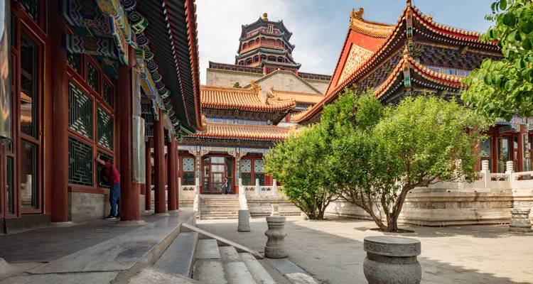 Patio de palacio chino histórico con aleros intrincados, columnas rojas y un pabellón imponente de estilo pagoda.