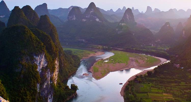 Curva panorámica del río Li enmarcada por picos kársticos verdes dentados bajo una suave luz vespertina.