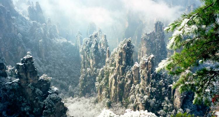 Snow-dusted quartzite peaks and evergreen forests of Zhangjiajie create a dramatic winter scene.