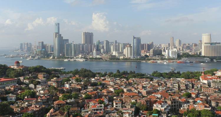 Uitgestrekt stadsaanzicht van Xiamen met moderne wolkenkrabbers aan de overkant van de haven en huizen met pannendaken op de voorgrond