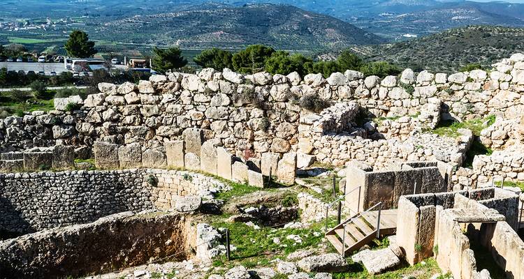 Murs de pierre et zone circulaire de tombes de l'ancienne Mycènes surplombant des collines ondulantes.