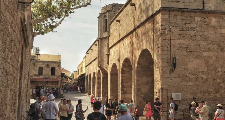 Druk middeleeuwse straat in de oude stad van Rhodos met warme stenen bogen en toeristen die aan het verkennen zijn.