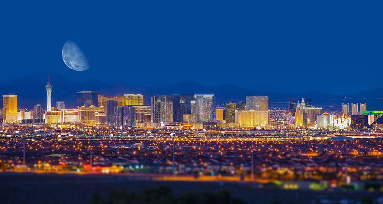 Panorama nocturne du Strip de Las Vegas illuminé sous une lune géante.