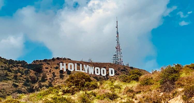 Le panneau Hollywood emblématique perché sur une colline aride sous un ciel bleu avec des nuages légers.