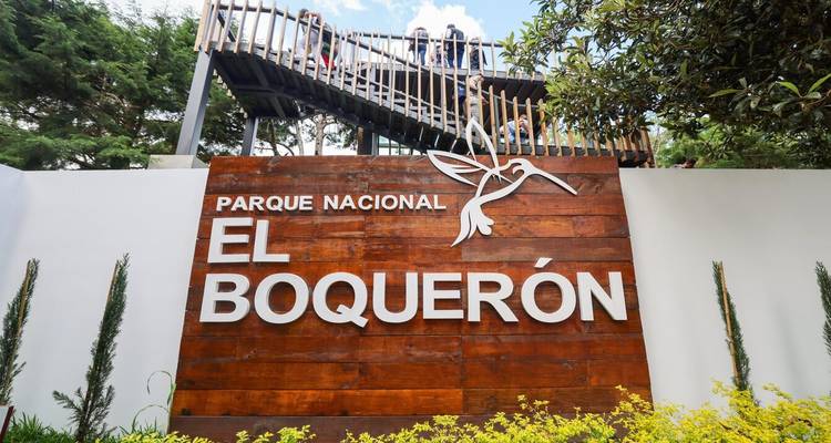 Panneau d'entrée du Parque Nacional El Boquerón fait de bois rustique avec logo de colibri et plateforme d'observation au-dessus.