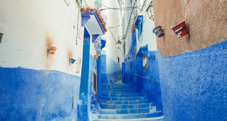 Smalle blauwe doorgang met trap in Chefchaouen's medina zonder mensen, badend in zacht daglicht.