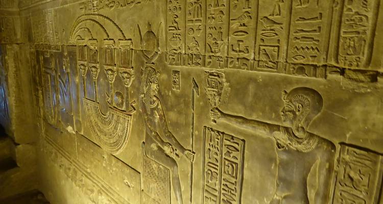 Primer plano de jeroglíficos detallados y tallados en una pared de templo antiguo bañada en luz cálida.