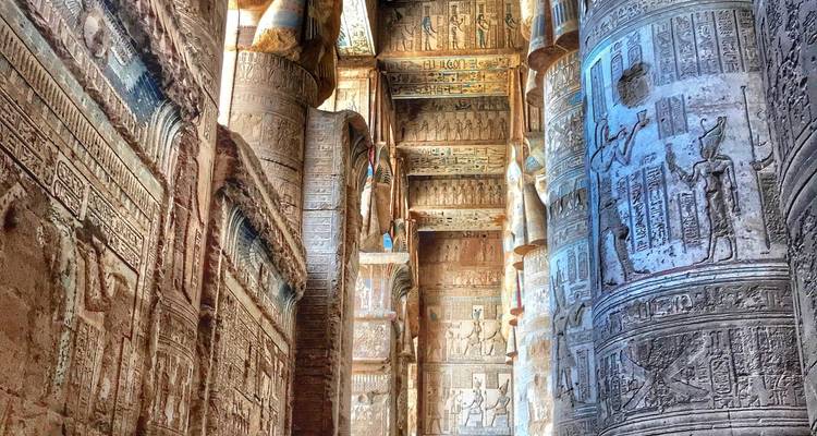 Imponentes columnas de piedra ricamente talladas with jeroglíficos bordean el salón de un antiguo templo egipcio.