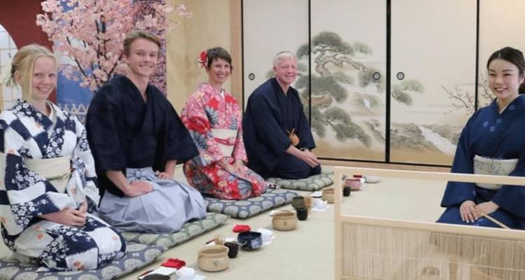 Small group wearing traditional yukata seated on tatami for Japanese tea ceremony.