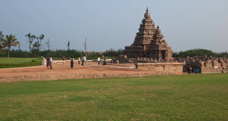 Bezoekers wandelen rond de oude Kustemp tegen de achtergrond van verzorgde gazons in Mahabalipuram