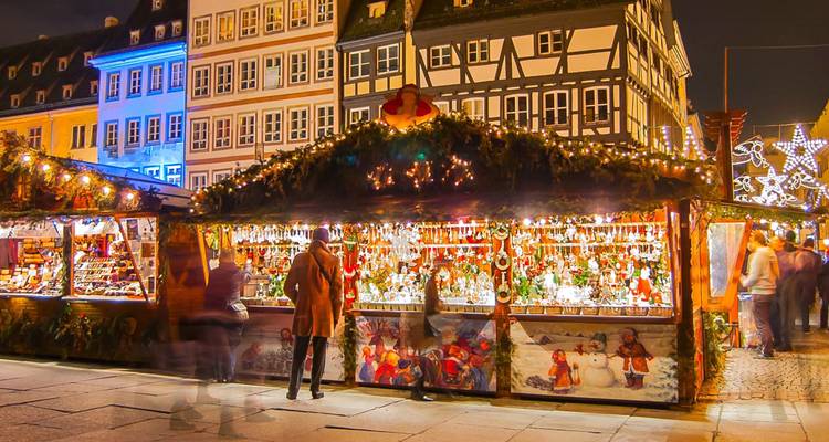 Traditionelle Holzstände voller Schmuck auf einem belebten europäischen Weihnachtsmarkt in der Nacht