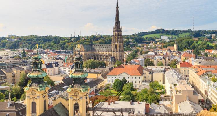 Vue panoramique sur Linz avec les tours jumelles de l'église et les collines verdoyantes ondulées au-delà de la ville.