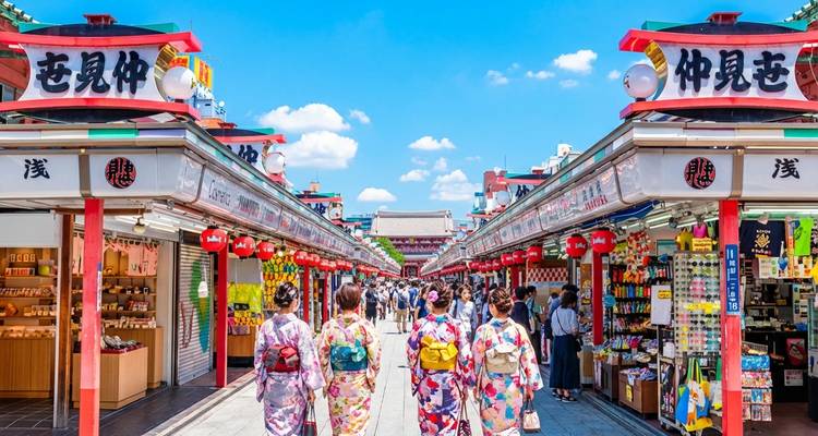 Vier vrouwen in kleurrijke yukata lopen door de levendige Nakamise winkelstraat vol met kramen en lantaarns in Asakusa.