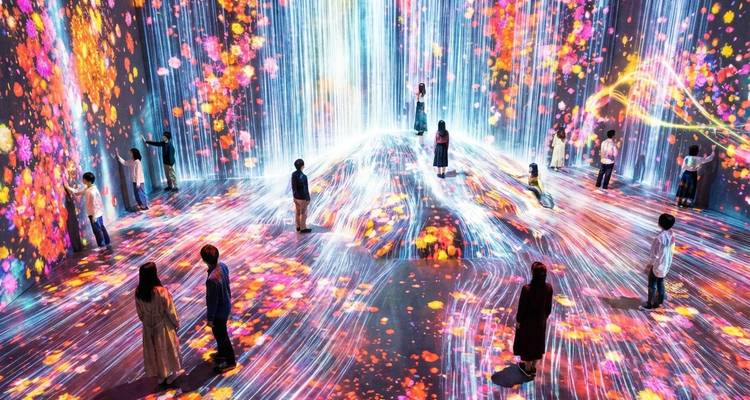 Meeslepende digitale kunstinstallatie met waterval van lichten en bloemenprojecties waar bezoekers door de levendige ruimte wandelen.