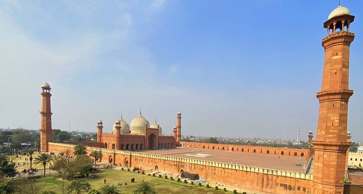 Vista expansiva de la Mezquita Badshahi de arenisca roja y su patio bajo el cielo azul claro de Lahore