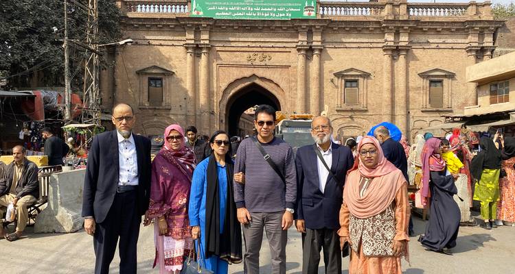 Grupo familiar sonriendo afuera del área histórica de la Puerta de Delhi en la ciudad amurallada de Lahore