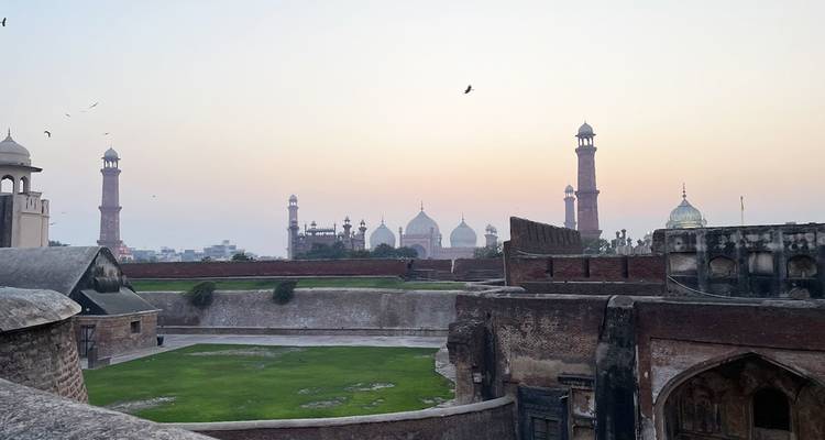 Horizonte de la Mezquita Badshahi y minaretes más allá de las murallas del Fuerte de Lahore al amanecer pastel.