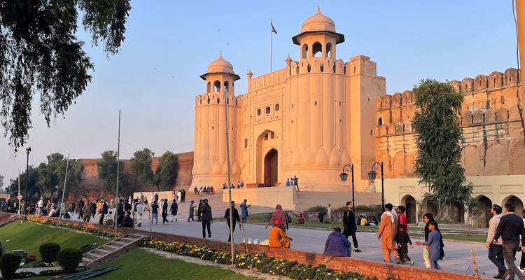 Los visitantes pasean fuera de la imponente Puerta Alamgiri del Fuerte de Lahore en una tarde despejada.