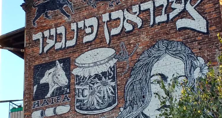 Mural de ladrillo colorido con letras hebreas, motivos de caballo y tambor en el barrio judío de Cracovia