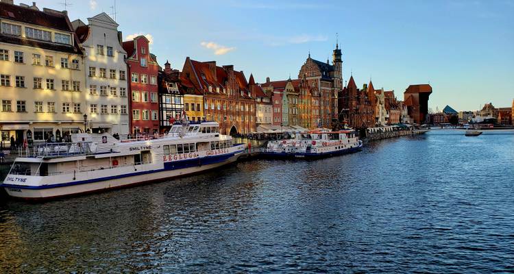 Vue panoramique au bord de la rivière de Gdansk avec des bateaux d'excursion amarrés le long d'entrepôts médiévaux colorés.
