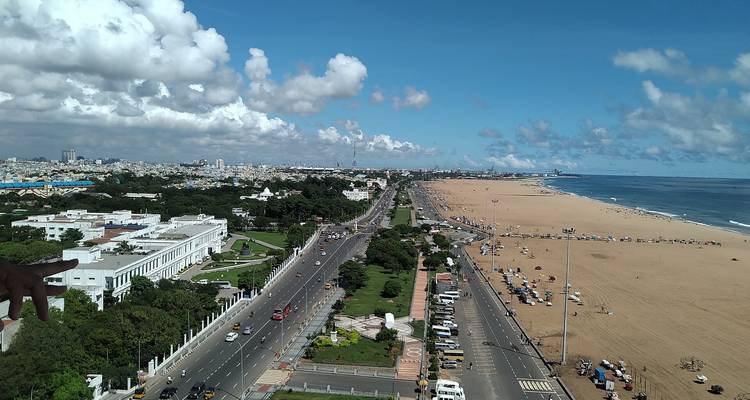 Luchtfoto van lang stadsstrand, drukke kustweg en skyline van de stad onder blauwe lucht