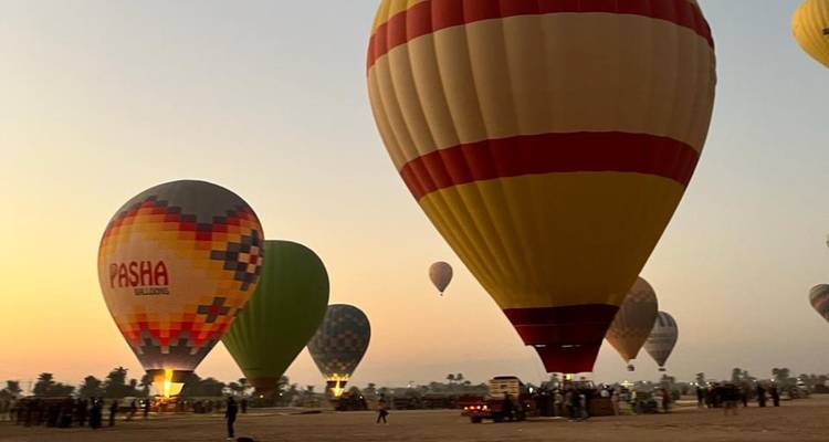 Los coloridos globos aerostáticos se inflan al amanecer sobre un paisaje desértico mientras los pasajeros se preparan para el vuelo.