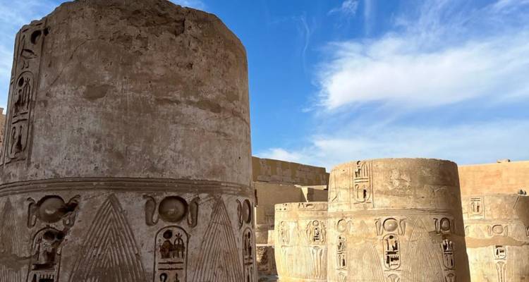 Masivos pilares cilíndricos decorados con jeroglíficos se alzan contra un cielo egipcio azul.