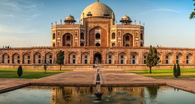 Symmetrische Frontalansicht von Humayuns Grab, das sich in einem langen Wasserbecken unter warmem Nachmittagslicht spiegelt.