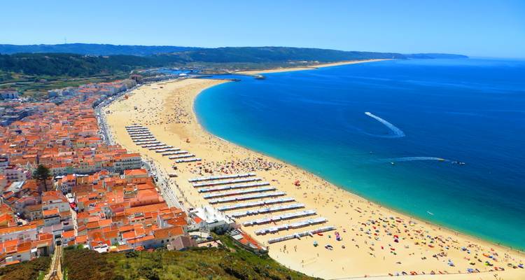 Aerial view of long golden beach curving beside turquoise Atlantic waters at Nazaré.