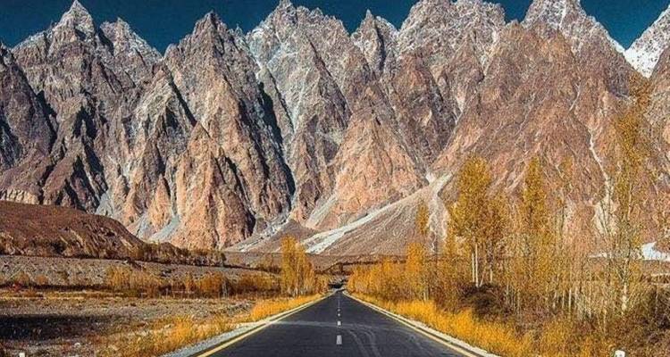 Route droite menant vers les spectaculaires montagnes dentées des Cônes de Passu aux couleurs automnales