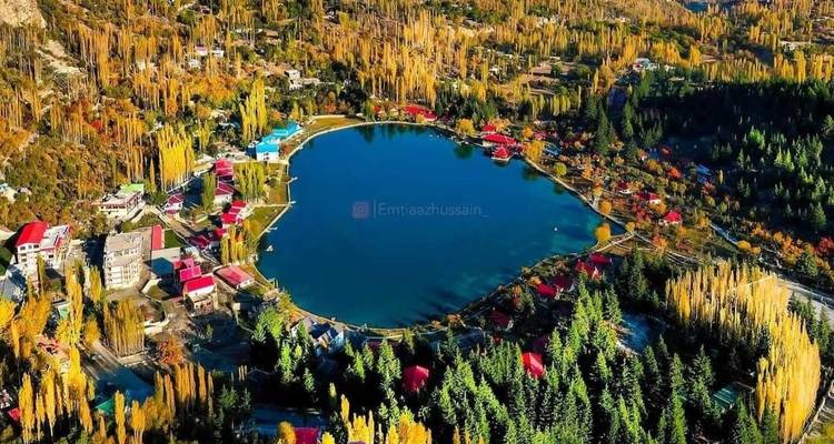 Vue aérienne d'un lac en forme de cœur entouré de toits colorés et d'arbres d'automne